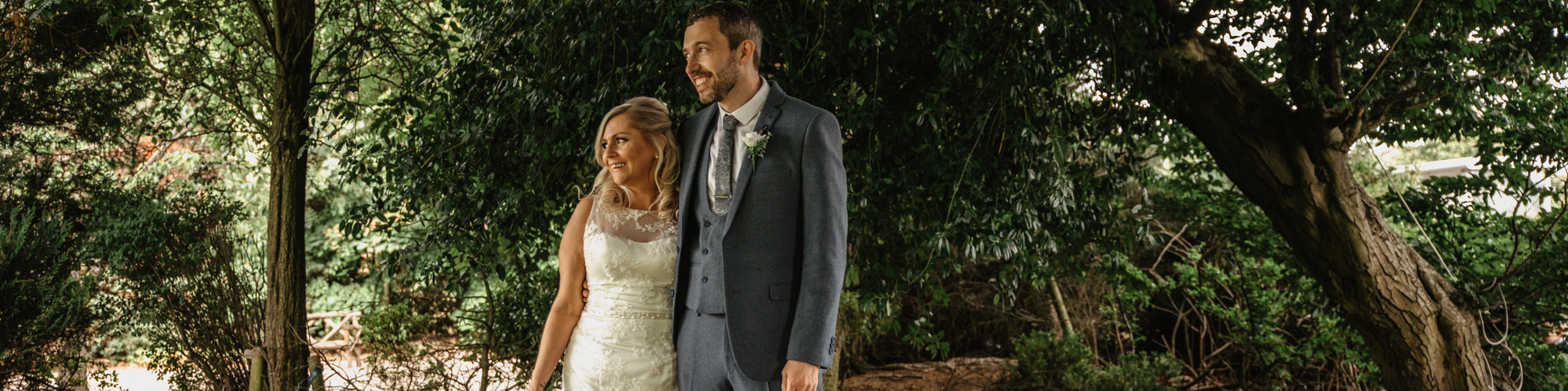 bride and groom looking off into distance under trees