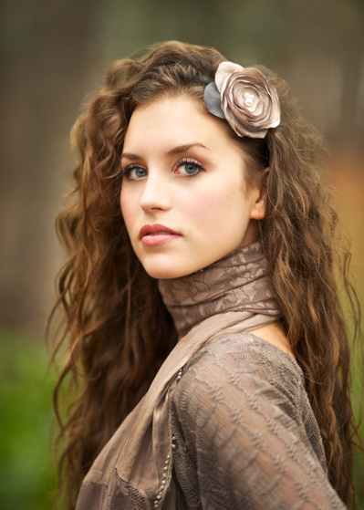 Gorgeous young brunette woman, outdoor headshot with flower in her hair