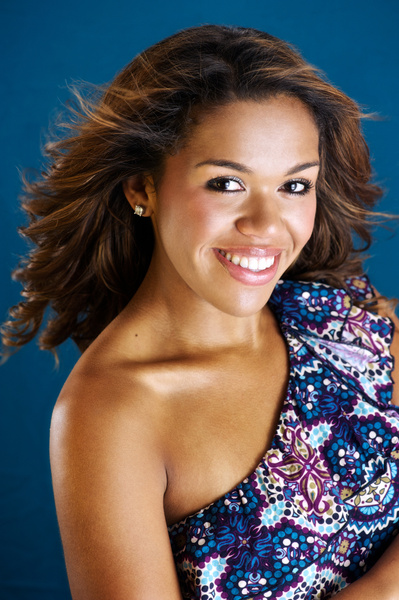 Young attractive black woman smiling headshot in Studio with flowered top.