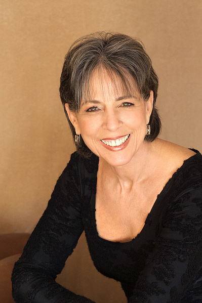 Pretty older woman 3/4 body shot in Studio wearing black top.