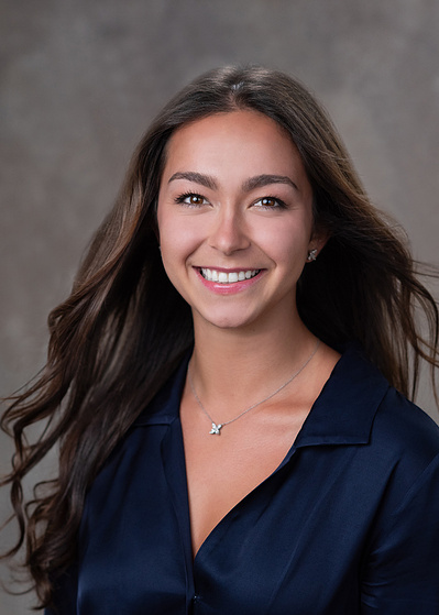 Studio headshot of pretty young woman wearing a navy blouse, smiling