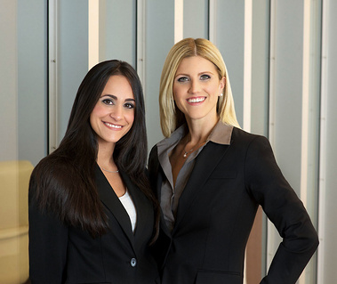 Two attractive female lawyers standing next to each other against vertical stripe wall