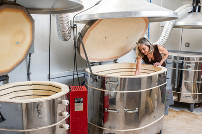 Female artist leaning into a kiln
