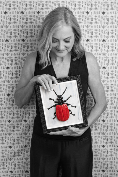 B&W photo of a female artist holding one of her creations in color
