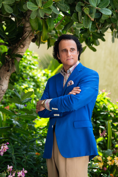 Attractive male opera singer standing in garden wearing a bright blue suit