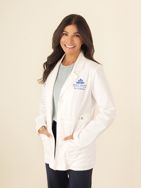 Pretty brunette Female doctor standing in a white lab coat smiling