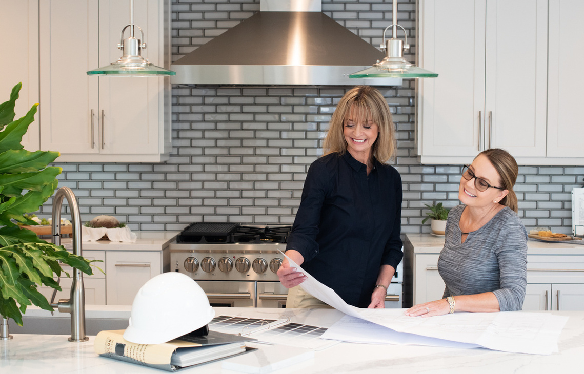 Pretty Female kitchen designer reviewing plans with her client