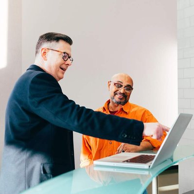 Retouching "after" edit example. Two men having a relaxed business meeting in an office lobby with the background changed to a more neutral setting using photoshop retouching.
