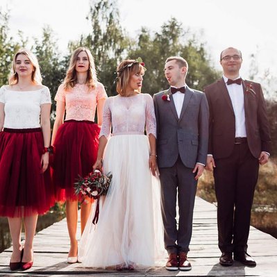 Retouching "after" edit example. A wedding party of 5 people smile and pose for a wedding photo on a lake jetty. one person has been removed using photoshop retouching.