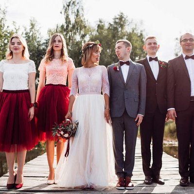 Retouching "before" edit example. A wedding party of 6 people smile and pose for a wedding photo on a lake jetty.