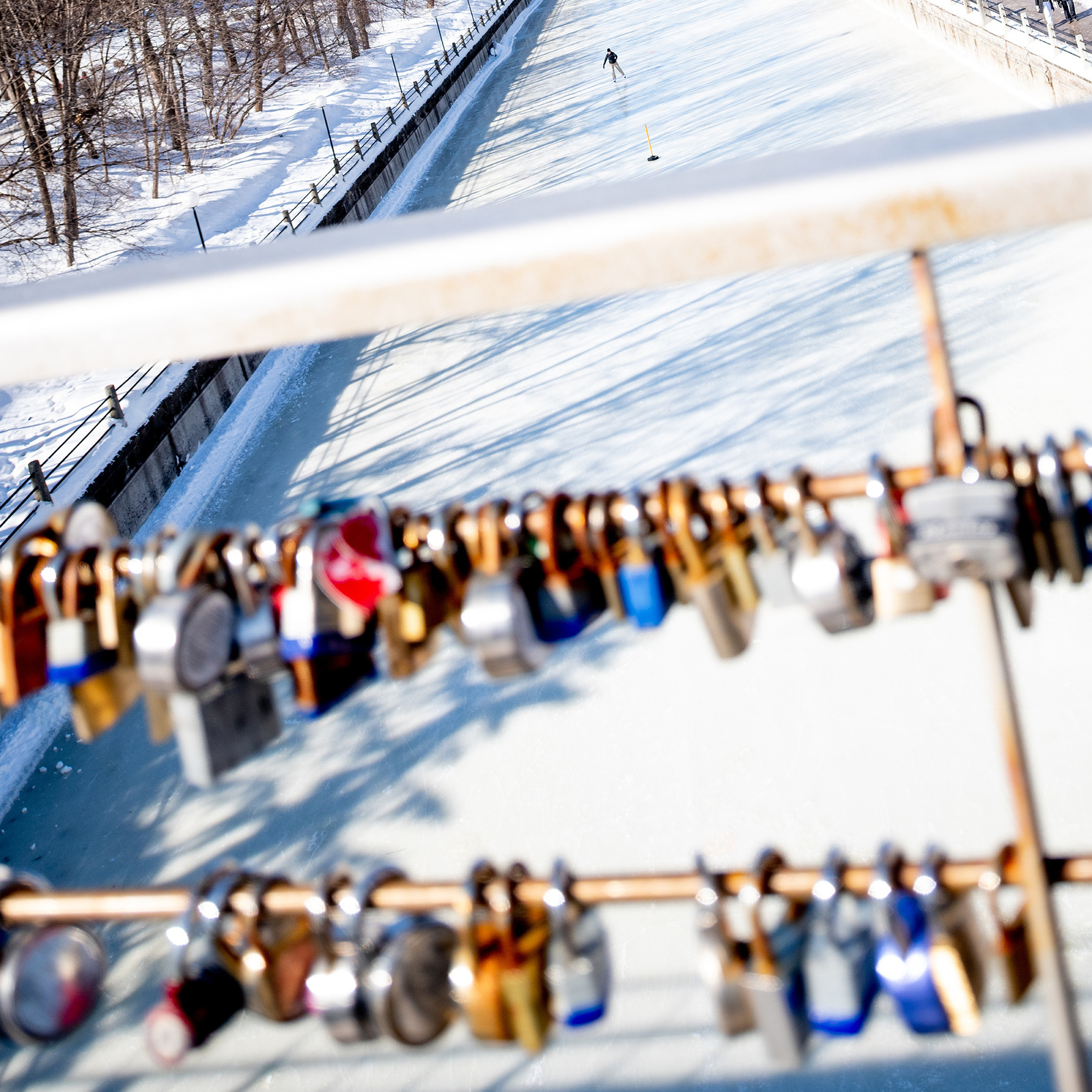 Rideau Canal with one skater on ice with blurry locks on lock bridge