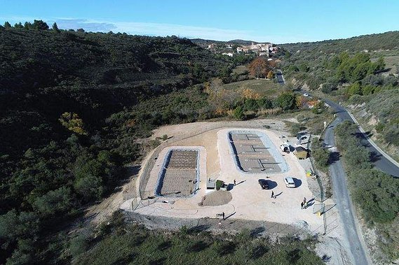 Une station d'épuration adaptée au traitement des eaux usées du petit village visible au loin