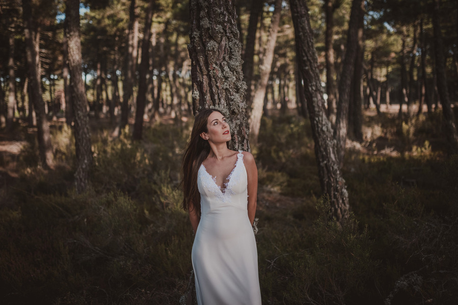 mujer apoyada en un árbol con vestido de novia