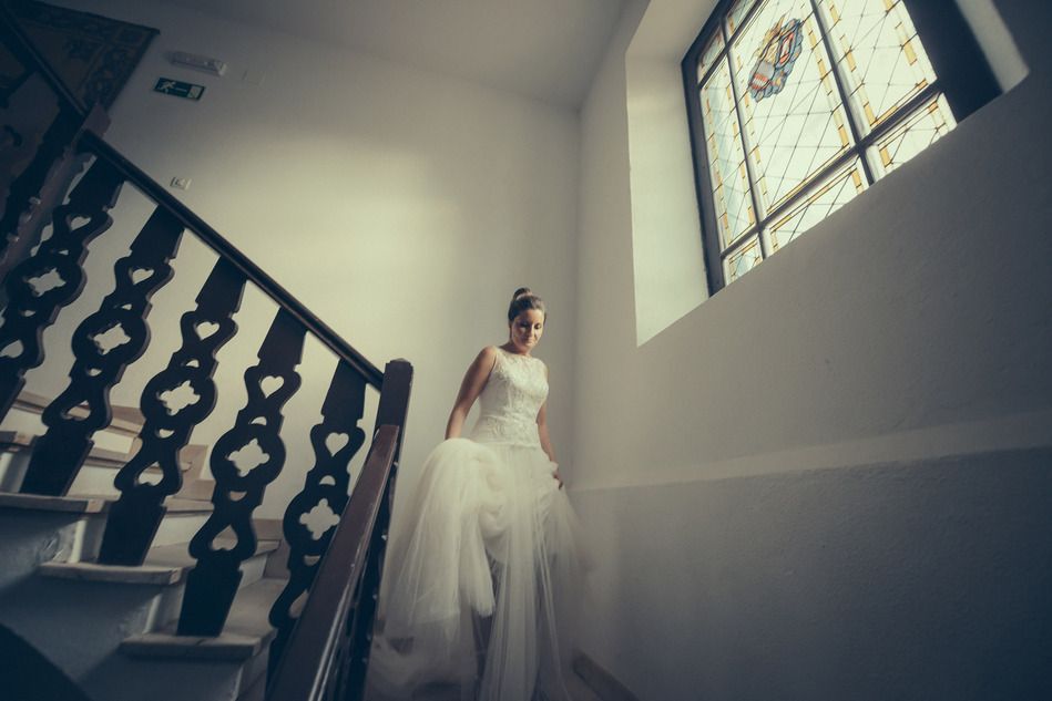 una novia baja por las escaleras con un ventanal grande a la derecha