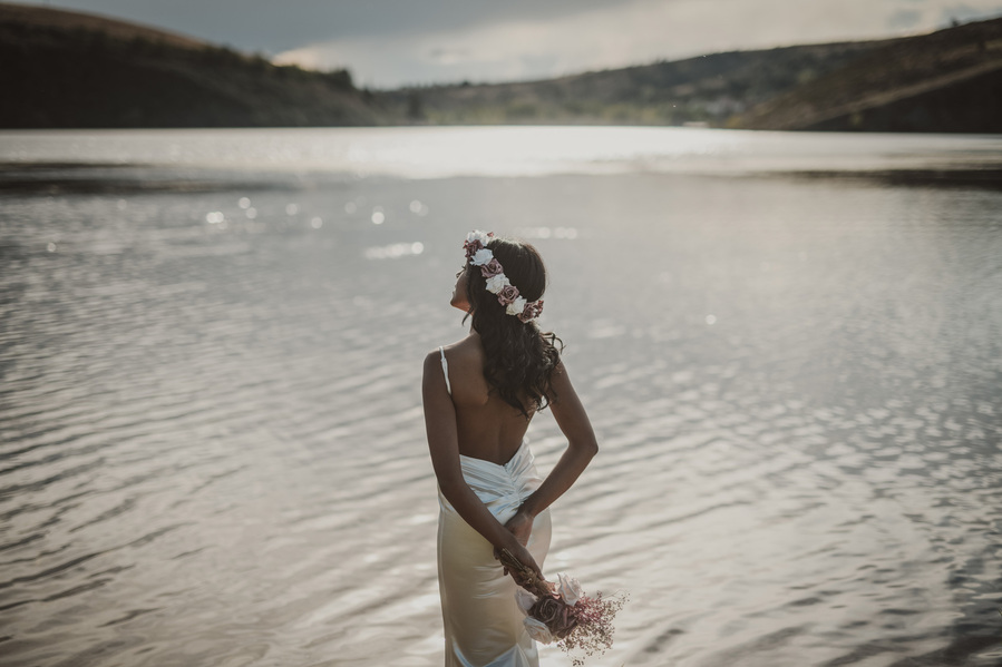 una mujer con vestido de novia mirando un lago