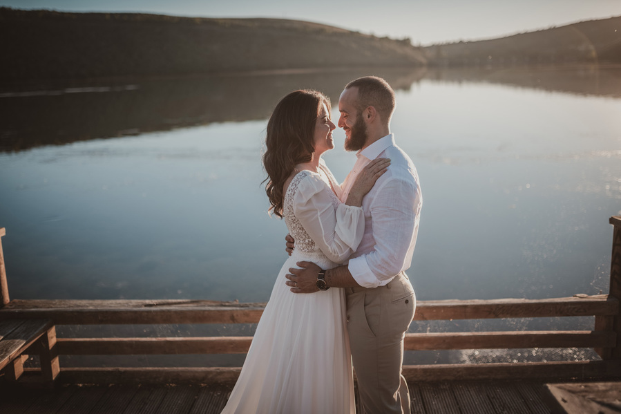 pareja de novios abrazandose en un lago a la puesta de sol