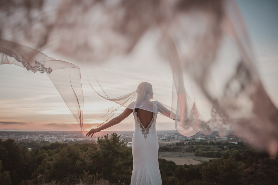 novia con el velo al viento a la puesta de sol