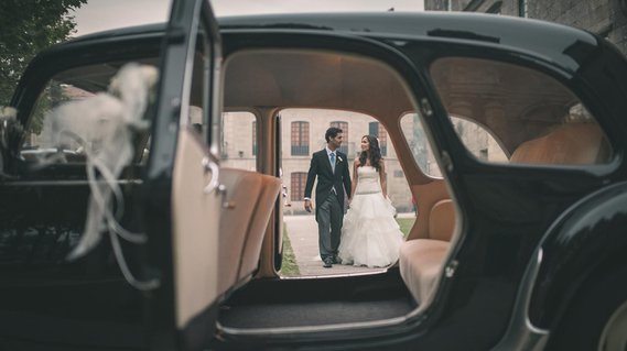 una pareja de novios se miran y caminan hacia un coche