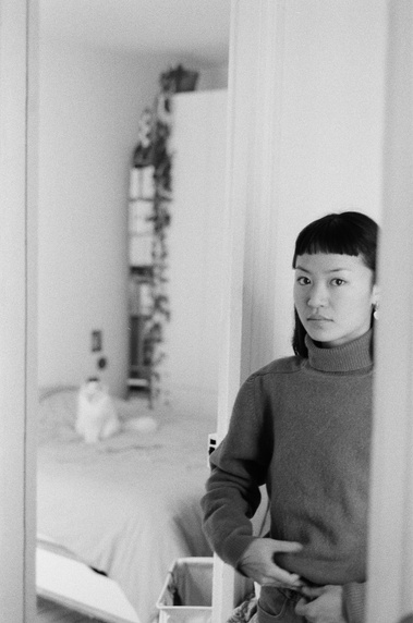 Julia Lê's portrait. Taken in a mirror at home, with a cat on the bed. ©Adrien Clayette