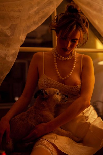 Woman posing with her dog for her boudoir photo shoot  in Amsterdam wearing white lingerie and jewelry