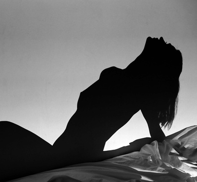 A woman posing on her bed during a boudoir photo session in black and white photography 