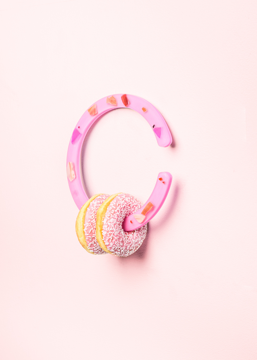 Haus Üger Loop i pink, hængende på vægen med to donuts.