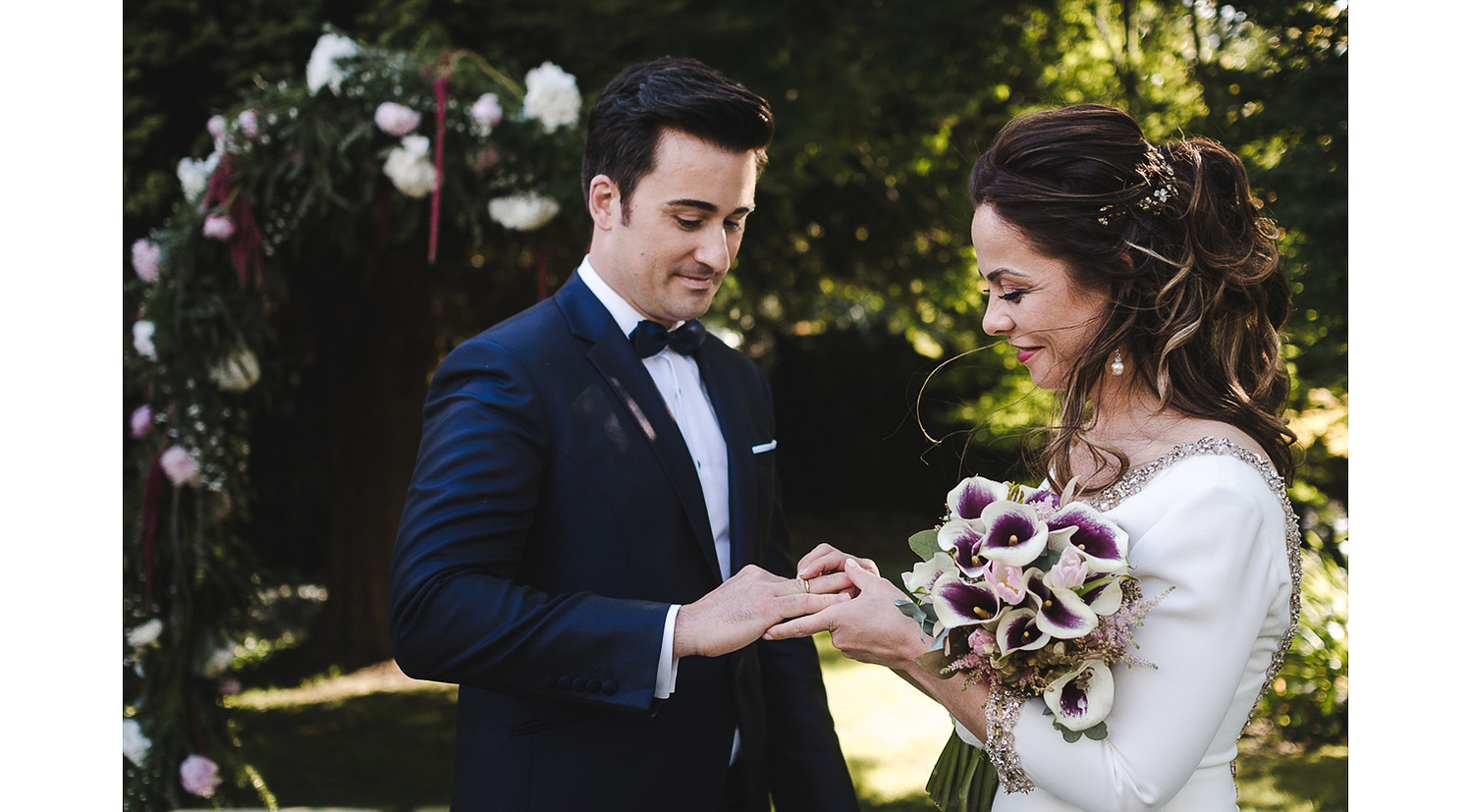 Novia le pone alianza al novia durante boda civil en Hotel NH Santiago de Compostela en el jardín. 