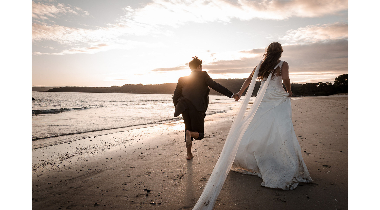 Fotografía de post boda en la playa en Galicia novios corriendo descalzos en la arena. Playa de Nerga.