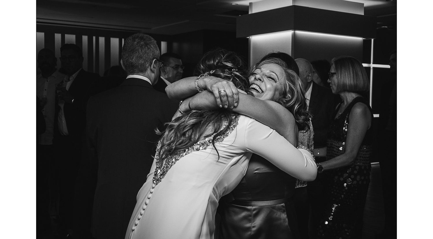 Madre abraza a novia durante la barra libre de la boda.