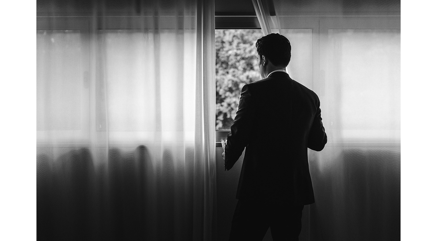 Novio en la ventana en blanco y negro antes de la boda