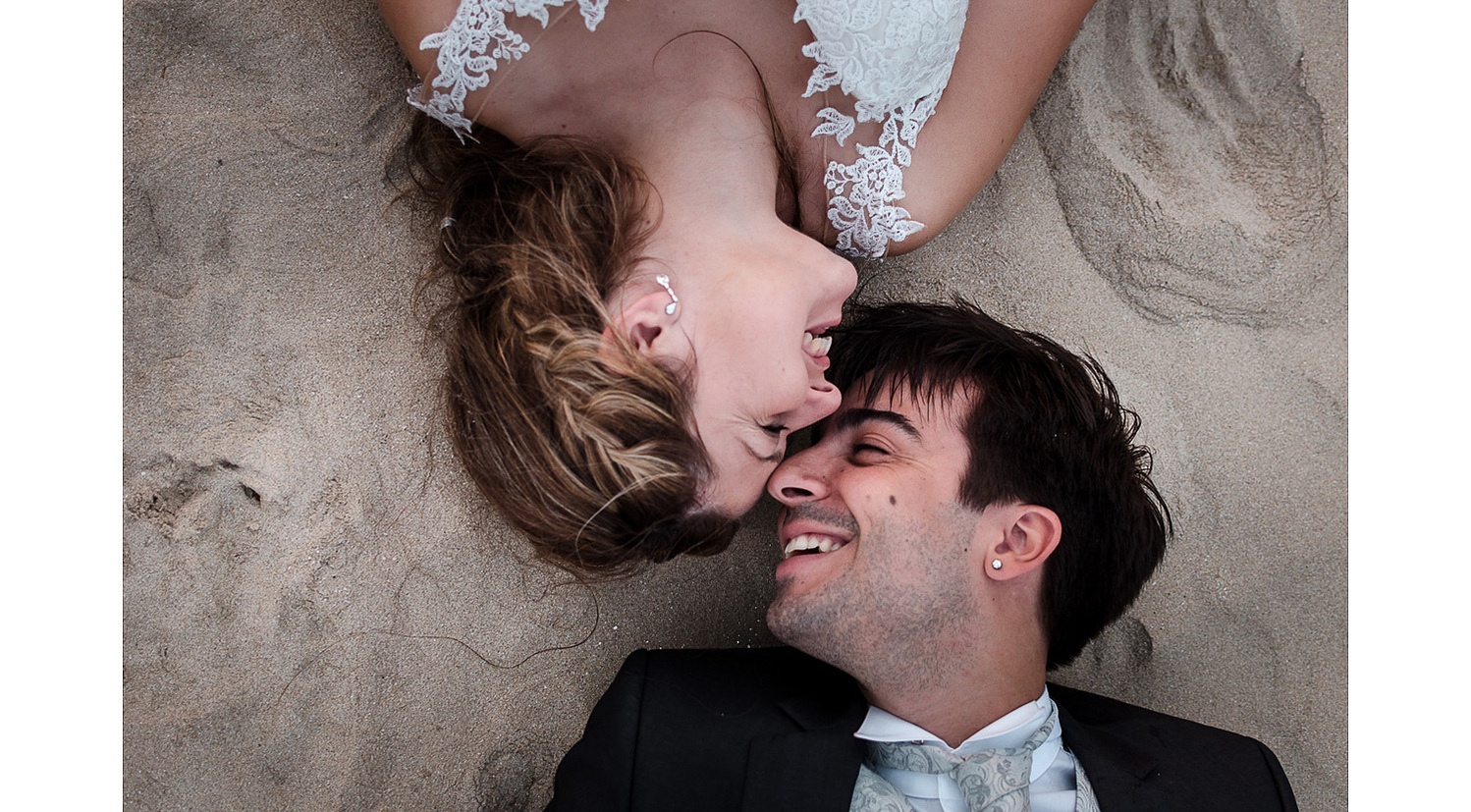 Post boda en la playa, novios acostados en la arena enamorados