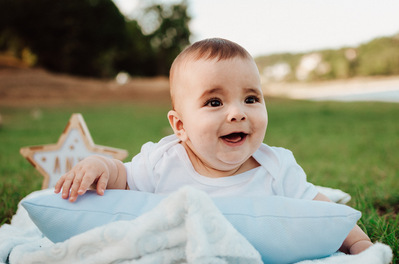 Reportaje fotográfico de bautizo en Ourense. Niño feliz riendo con puesta de sol en el Embalse de Cachamuiña.