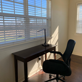 Desk, lamp, and chair near a window with a view of the countryside. 