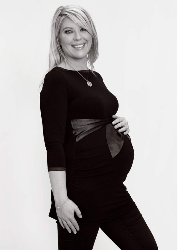 Natural  maternity portrait photo in professional photography studio using white background, side view of pregnant woman bump wearing black clothes to accentuate the pregnant bump 