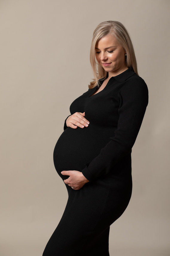 Natural  maternity portrait photo of a pregnant mother in professional photography studio with her hands placed  on her pregnant bump
