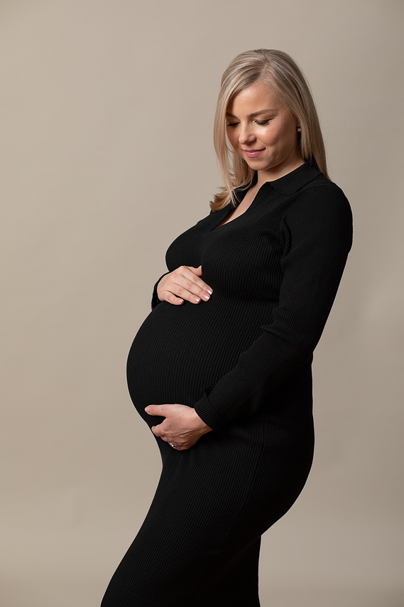 Natural  maternity portrait photo of a pregnant mother in professional photography studio with her hands placed  on her pregnant bump
