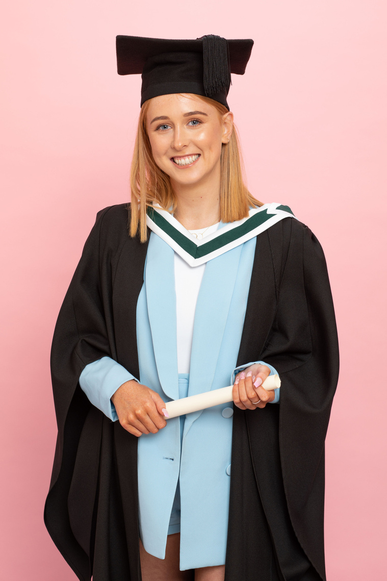 young female graduate student in photo studio graduation photographer dublin pink background