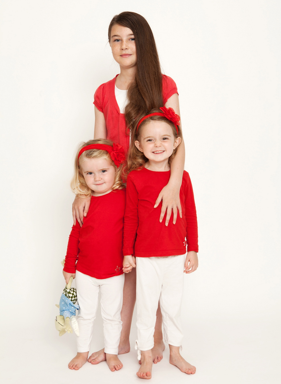 Professional Christmas portrait of mother and two daughters wearing red and white in a professional family portrait photography studio in Dublin with white background 