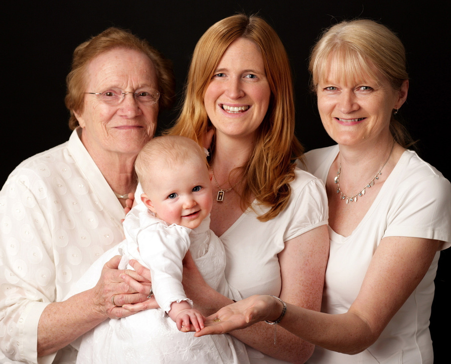 Great Grandmother, grandmother, mother, and granddaughter 4 generations of the same family in a generational portrait taken in a professional family photography studio in Dublin black background