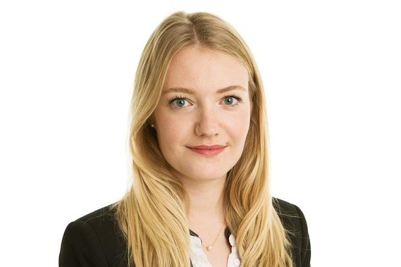 Professional business headshot of young female with blonde hair and black jacket in photography studio with plain white background 