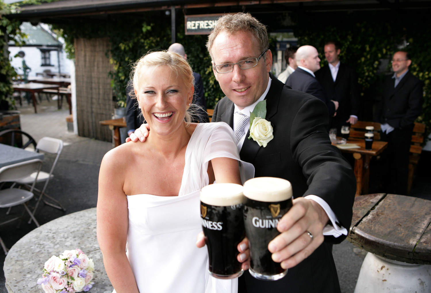 Fun wedding portrait of bride and groom smiling and holding two pints of Guinness professional wedding photographer Dublin Ireland 