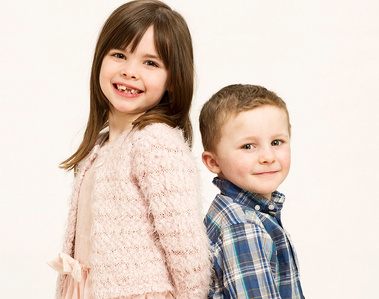 Portrait of Sister and brother back to back smiling in professional family photography Studio 