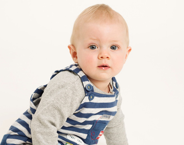 Professional portrait of a Baby boy in stripy dungarees white background