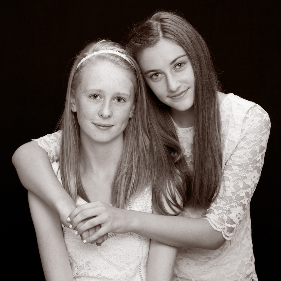 Classic black and white portrait of two teenage sisters wearing white in professional family photography studio 