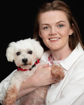 Professional Family Portrait of teenage girl holding her small white dog in photography studio with black background. Christmas gifts for dog lovers