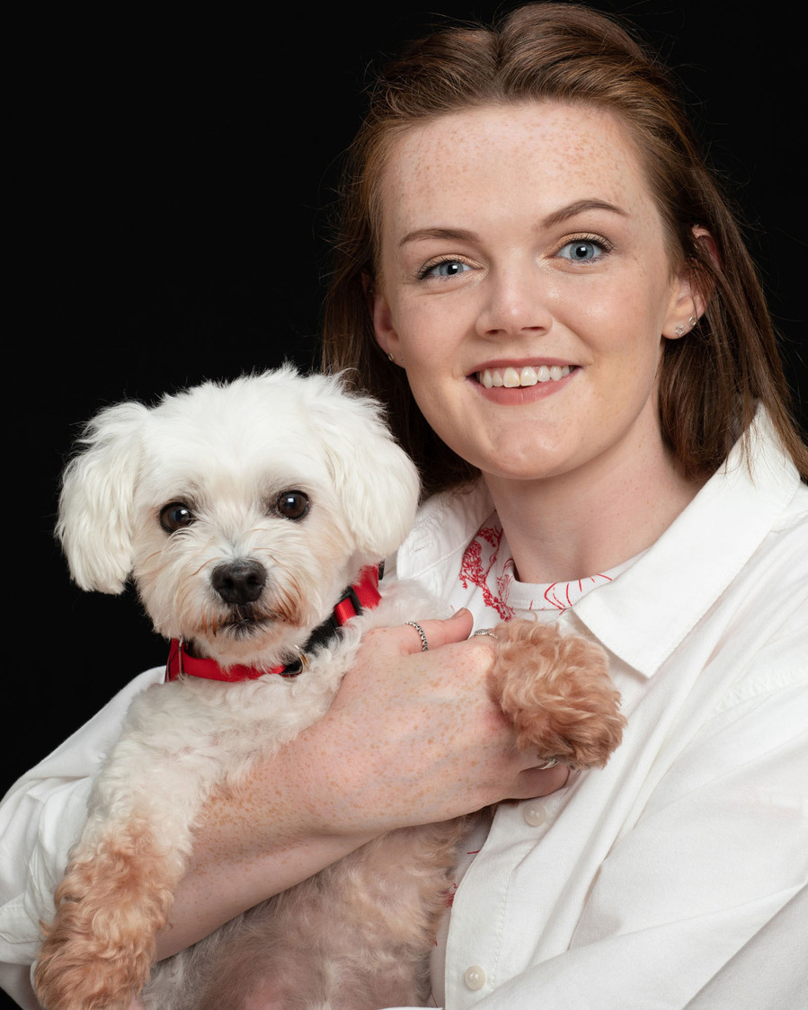 Pet portrait photography studio. Owner and small white dog portrait in a professional family photo studio black background