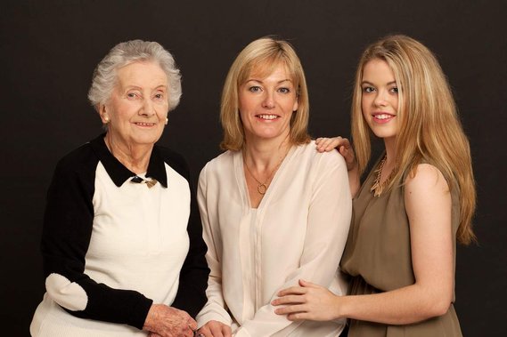 Grandmother, daughter and granddaughter generational studio portrait black background