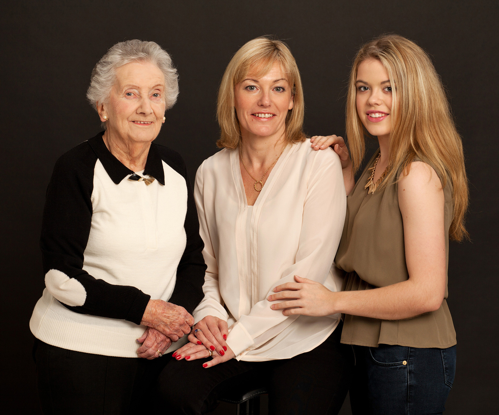 Professional generational portrait of Great Grandmother, Mother and Granddaughter in photography studio with black background 