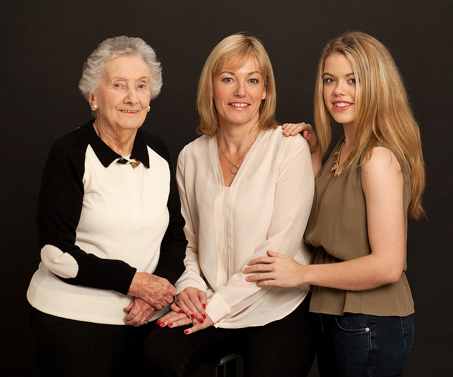 Grandmother, daughter and granddaughter generational studio portrait black background professional photographer