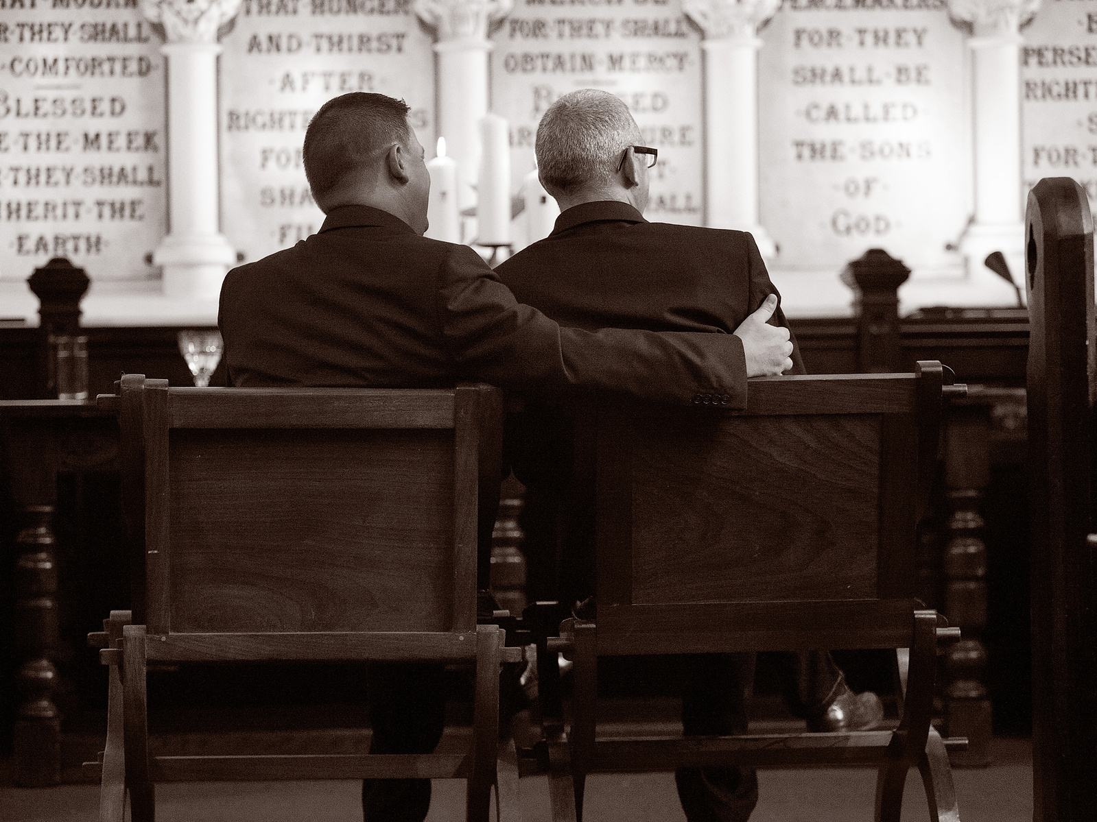 Groom and Groom gay couple sitting together in Dublin Unitarian Church at civil wedding ceremony in Dublin Ireland professional photographer